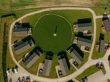An outdoor area with houses surrounding a pond at Pine Lodge Spa Carlton Miniott near Thirsk