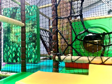 A play area with a play structure featuring netting and a slide at Pine Lodge Spa Carlton Miniott near Thirsk
