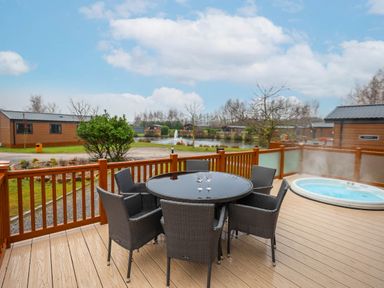 An outdoor space with a table and chairs plus a hot tub at Laurel Waterside Spa Carlton Miniott near Thirsk