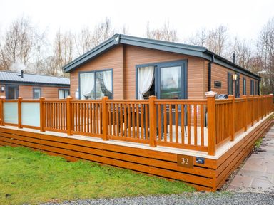 A house with decking and a railing at Laurel Waterside Spa Carlton Miniott near Thirsk