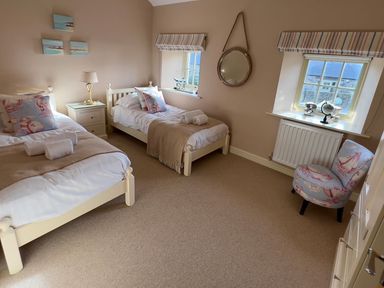 A bedroom with two beds and a bedside table at The Chimney in Bamburgh