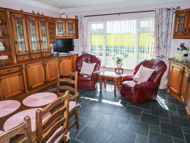 A kitchen with wooden cabinets and red armchairs at Marie's Country Home, Ardee, County Louth