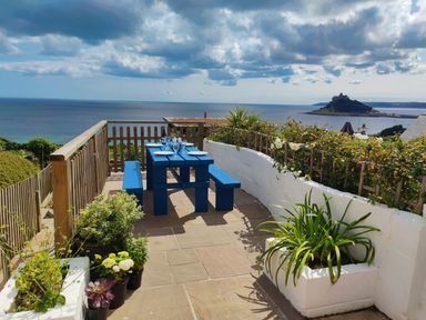An outdoor dining area with a blue table and benches at Ty Bryn in Marazion