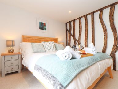 A bedroom with a bed, bedside table, and towels at Ty Bryn Marazion