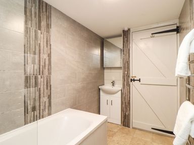 A bathroom with a bathtub, sink, and mirror at Ty Bryn in Marazion