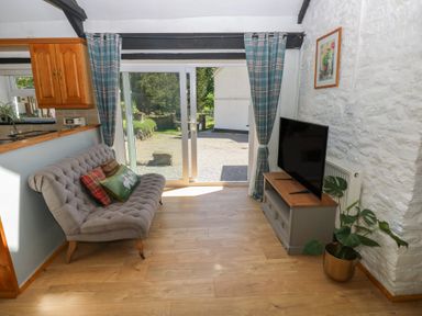 A living room with a sofa and television at Daffodil Cottage in Blaencwm near Treorchy