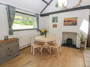 A dining room with a table and chairs at Daffodil Cottage in Blaencwm near Treorchy