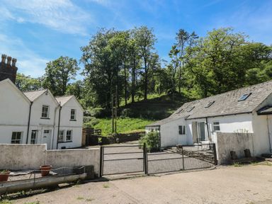 An outdoor view of houses with a gate and trees at Daffodil Cottage in Blaencwm near Treorchy