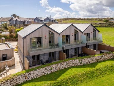 Modern houses with balconies and a stone wall at Clifftop House Hot Tub, St Ives