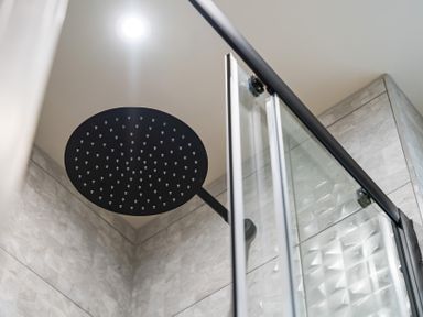 A shower area with a round shower head and glass door at tbc in St. Ives