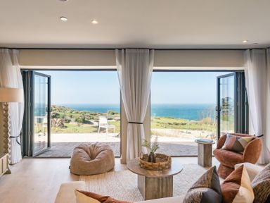 A living room with a coffee table and sofa overlooking the ocean at tbc St. Ives