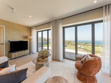 A living room with a television and large windows at tbc in St. Ives