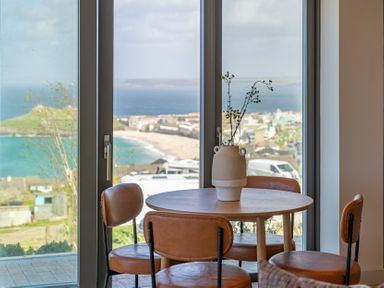 A dining room with a table and chairs overlooking the sea at tbc in St. Ives