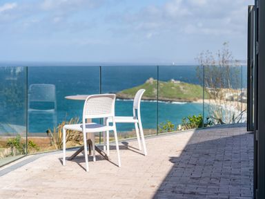 An outdoor patio with a table and chairs overlooking the sea at tbc in St. Ives