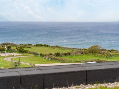 An outdoor view of the ocean with grassy area and benches at tbc in St. Ives