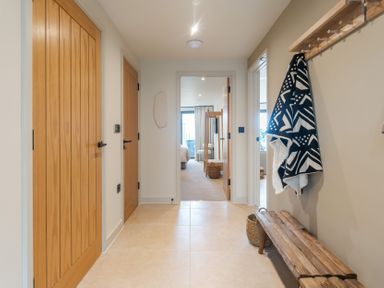 A hallway with wooden doors and a bench at tbc St. Ives