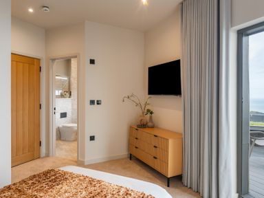 A bedroom with a dresser and television at tbc in St. Ives