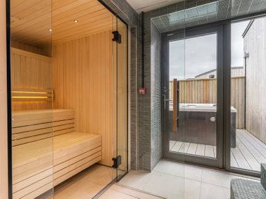 A sauna with a hot tub visible through a glass door at Hidden 19- Coastal Hot Tub in St Ives