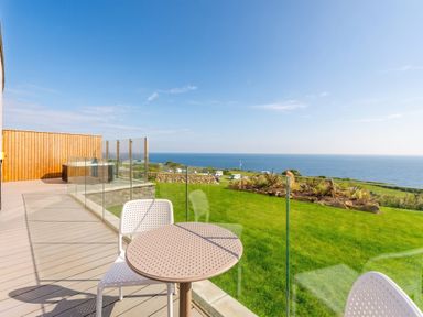 An outdoor area with a table and chairs overlooking the ocean at Hidden 19- Coastal Hot Tub, St Ives