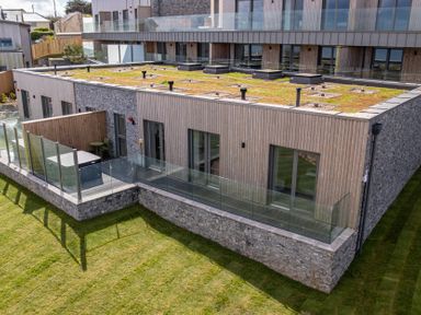 An outdoor area featuring a building with a glass railing and grass at tbc St. Ives
