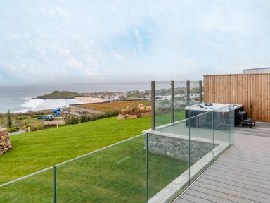 An outdoor area with a hot tub and grass overlooking the ocean at tbc in St. Ives