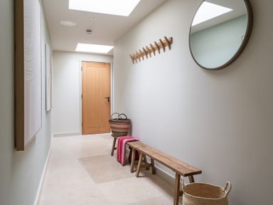 A hallway with a wooden door, mirror, and bench at tbc in St. Ives