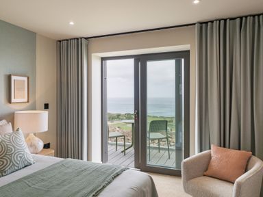 A bedroom with a bed and a door leading to a balcony at tbc St. Ives