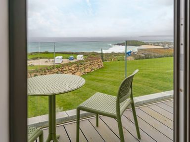 An outdoor seating area with a table and chair overlooking the ocean at tbc in St. Ives