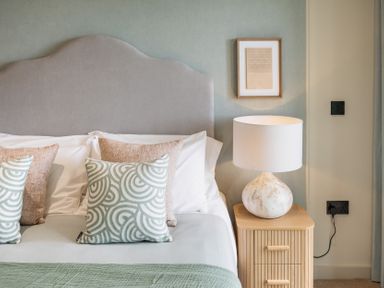 A bedroom with a bed, decorative pillows, lamp and nightstand at tbc in St. Ives