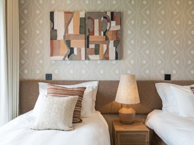 A bedroom with two beds and artwork on the wall at Hidden 10- Godrevy View, St Ives