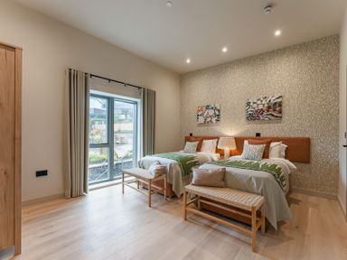 A bedroom with two beds, a window, and wall art at tbc in St. Ives