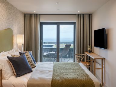 A bedroom with a bed, television, and sliding door at tbc in St. Ives