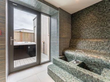 A bathroom featuring a hot tub and door at Hidden 13- Skyline Terrace St Ives