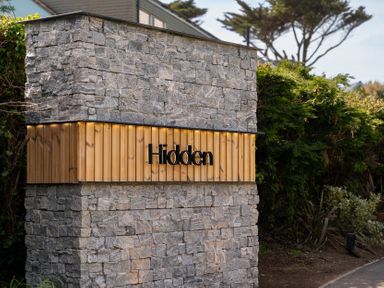 A stone wall with wooden panel and sign at Hidden 7- Coastal Loft in St Ives