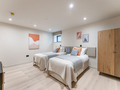 A bedroom with two beds and artwork on the walls at The Old Barn in St. Ives