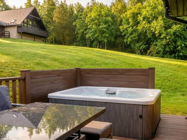 A hot tub and table on a deck at The Derwent Spa (Pet) Slaley