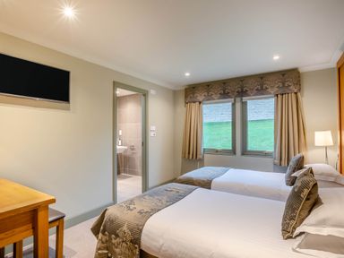 A bedroom with two beds and a desk at The Derwent Spa (Pet) in Slaley