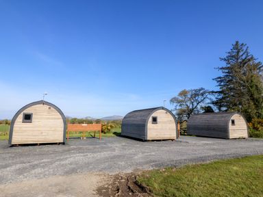 Three wooden pods with a sign in between at Bron Eifion Pod 1 Criccieth