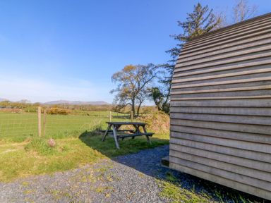 An outdoor area with a wooden pod and picnic table at Bron Eifion Pod 1 Criccieth