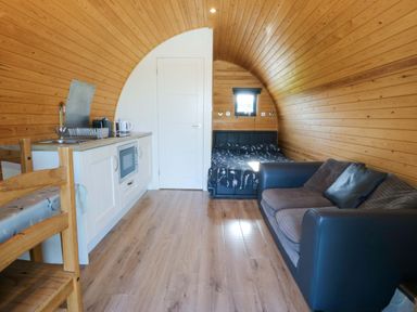 A living room with a kitchen area and sofa at Bron Eifion Pod 1 in Criccieth