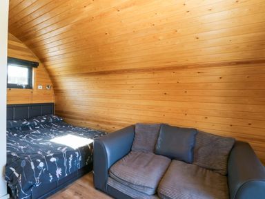 A bedroom with a bed and a sofa at Bron Eifion Pod 1 Criccieth