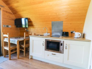A kitchen with a table and chairs at Bron Eifion Pod 1 in Criccieth
