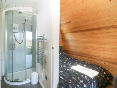A shower in bathroom and a bed in bedroom at Bron Eifion Pod 1 Criccieth