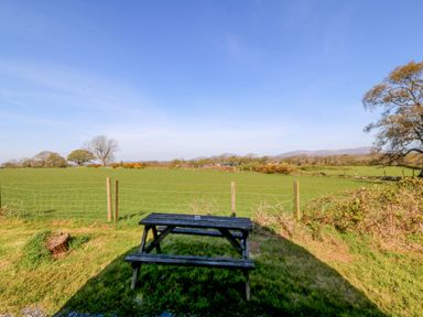 An outdoor area with a picnic table overlooking a field at Bron Eifion Pod 1 Criccieth