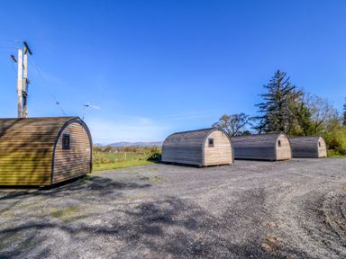 A series of wooden cabins in an outdoor area at Bron Eifion Pod 1 Criccieth