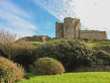 A castle with flags on top and greenery at Bron Eifion Pod 1 Criccieth