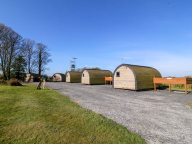 Several wooden pods in an outdoor area at Bron Eifion Pod 1 in Criccieth