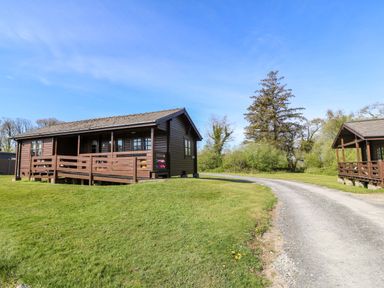A cabin with porch beside a gravel road at Lodge 2 - Bron Eifion