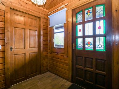 An entrance hall with a door and window featuring stained glass at Lodge 2 - Bron Eifion