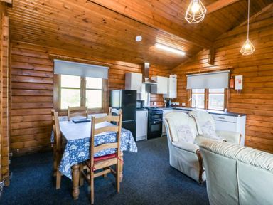 A kitchen with a table and chairs at Lodge 2 - Bron Eifion